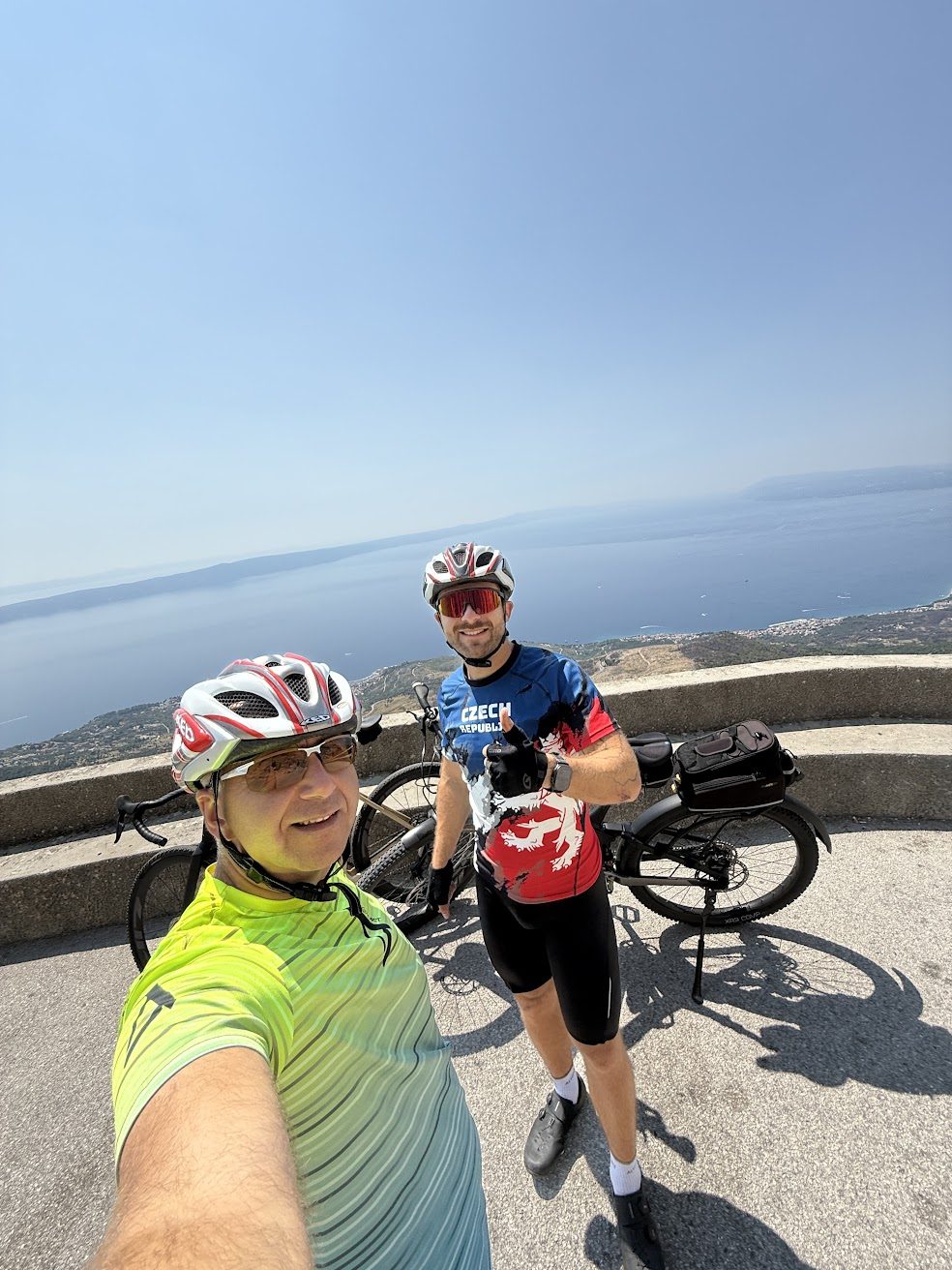 Dva kolesarja s kolesi na razgledni točki nad obalo